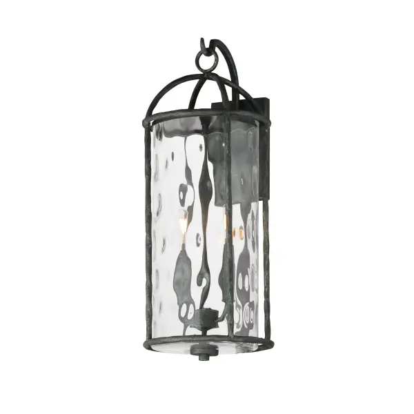 Inspired by classic European lanterns and handcrafted ironwork, the Del Mar collection brings timeless sophistication to exterior spaces. Its airy open-frame silhouette is crafted of hammered iron, elegantly arched with a graceful hook detail that nods to historic gas lamps. Inside the frame, a delicate Water glass cylinder shimmers with texture, diffusing light in a soft, atmospheric glow. Designed for lasting beauty in the elements, each piece is finished in a richly layered Blacksmith finish--a deep near-black tone highlighted by silvery brushstrokes, adding artisanal character to the silhouette. Whether flanking a grand entry or lining a garden path, Del Mar offers a refined approach to outdoor lighting with enduring presence.