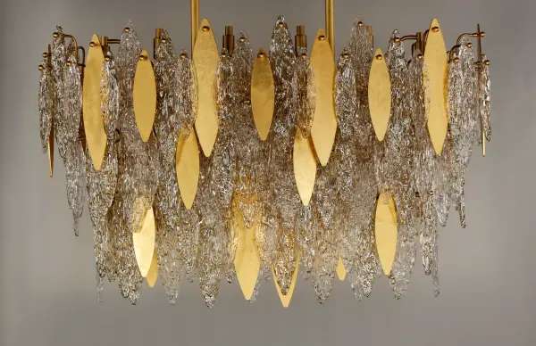 Hand-formed glass petals of Clear and Champagne-tint suspend from a tiered frame of gold and accented with petals of solid metal finished in Gold Leaf. Numerous candelabra sockets are strategically placed within the fixture to create glimmer and elegance to this majestic collection. - alternate view