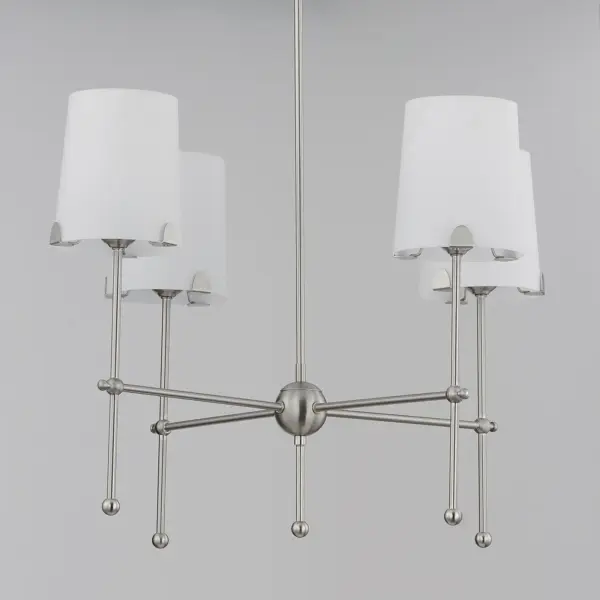 Satin White shades taper in a classic fabric shade shape and rest on elegantly thin frames of Satin Brass or Satin Nickel. They are supported secured by a mostly concealed structure with coordinating semicircular tabs that complement the spherical joints of the frame. The modern design details and updated shade materials refresh the outlook of a timeless chandelier though its use of thoughtful features. - alternate view