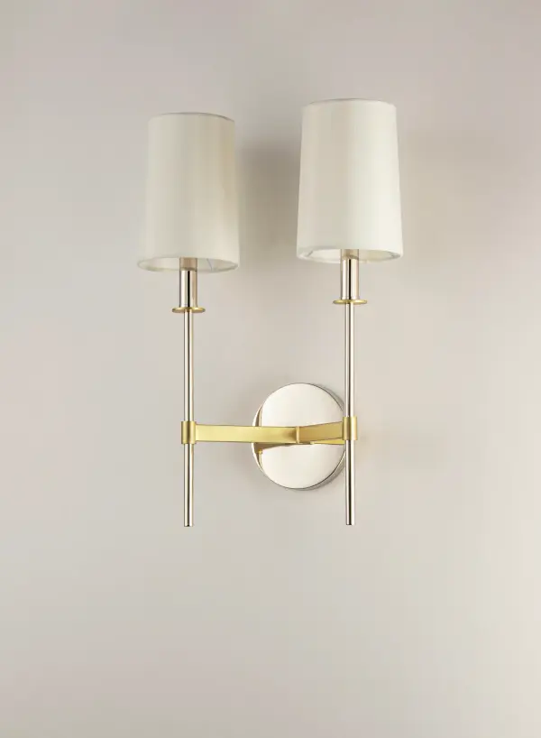 Elongated tails and candle sticks create effortless sophistication in the Uptown series. The slender candles of Polished Nickel contrast the stout supporting arms finished in a soft Satin Brass. Tall Off-White fabric shades complement the updated classic design. The simplicity of this design allows it to pair with various traditional to contemporary stylings and many color themes. - alternate view