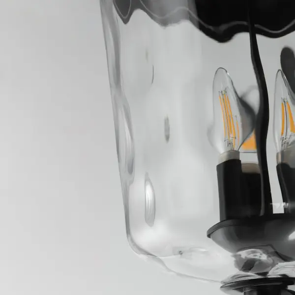 The Prescott collection of outdoor lanterns reimagines a classic design with timeless elegance. Crafted with a durable die-cast aluminum frame and finished in a sleek Matte Black, these lanterns exude a refined, understated charm. The water glass shade creates a beautiful lighting effect as it casts dazzling patterns on its surrounding surfaces. Thoughtfully updated with simple stirrup hook details, the collection effortlessly blends tradition with modern sophistication. - alternate view