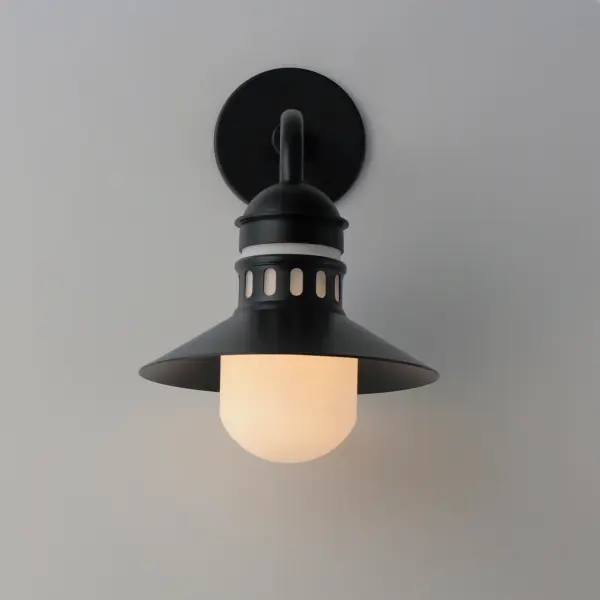 Coastally inspired, the wide brimmed aluminum spun shade on this series of outdoor rated sconces, pendants, and flush mounts features a tiered shade design. The ringed separation features a filigree of oval cut outs, whereby a single lamp illuminates the Satin White glass supporting it. The resulting light is dispersed both above and below the spun shade as well as through the patterned filigree. Both modern and classic homes can appreciate this classic design reimagined. The series is available either in Matte Black or a striking Two-Tone Black with Antique Brass. - alternate view