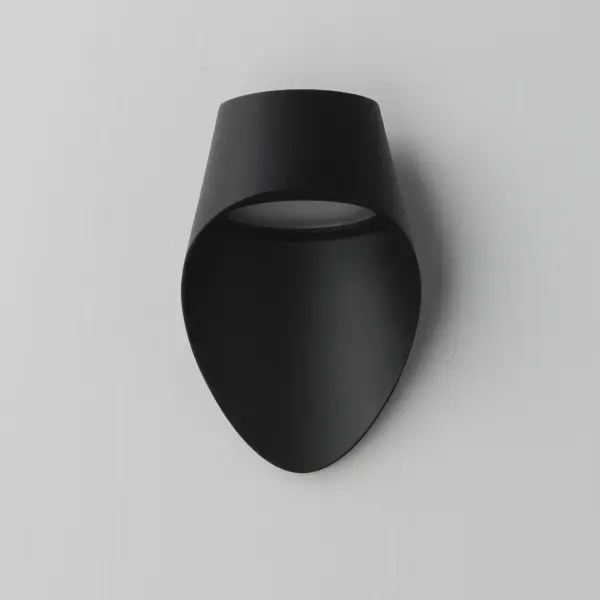 Compact yet stylish, the Cape outdoor sconce features an elongated backplate that elegantly shrouds a recessed LED module within its hood. Finished in contemporary Matte Black, this sconce delivers a unique lighting solution that is both functional and fashion-forward, perfect for modern outdoor spaces. - alternate view