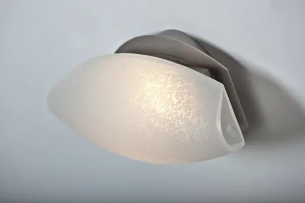 The Aero Stucco combines handcrafted textured glass with contemporary design, creating a striking diffuse glow. Its versatile oval canopy allows horizontal or vertical mounting, making it ideal for modern bath and vanity applications. - alternate view