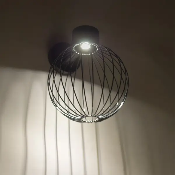 The Sultana Globe LED sconce brings urban sophistication to outdoor spaces with its black aluminum bracket and distinctive woven metal rod globe. The exposed hardware celebrates industrial design while the focused LED downlight creates dramatic sculptural effects.
