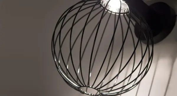 The Sultana Globe LED sconce brings urban sophistication to outdoor spaces with its black aluminum bracket and distinctive woven metal rod globe. The exposed hardware celebrates industrial design while the focused LED downlight creates dramatic sculptural effects. - alternate view