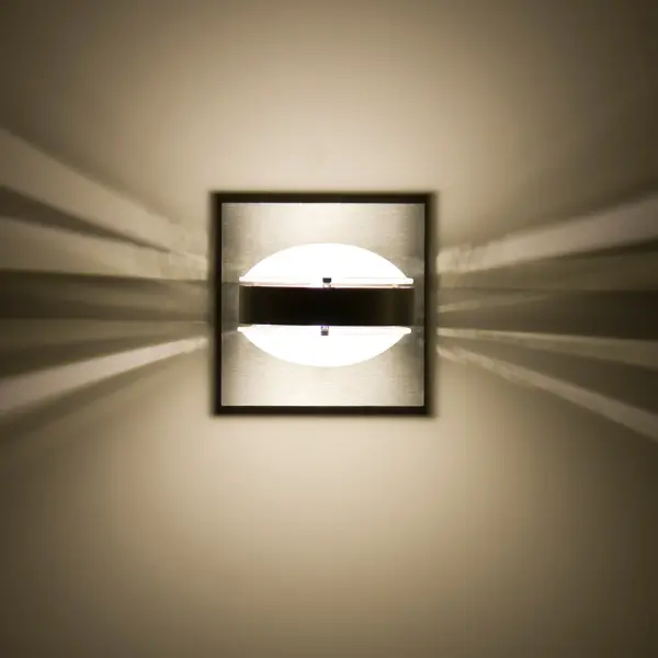 The Optos wall sconce features two optical-effect lenses that produce captivating displays of up and down light. With 359-degree rotation capability and handcrafted frosted borosilicate glass, it delivers functional yet vibrant illumination with an edgy, energetic aesthetic.