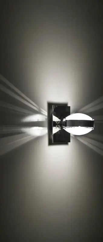 The Optos wall sconce features two optical-effect lenses that produce captivating displays of up and down light. With 359-degree rotation capability and handcrafted frosted borosilicate glass, it delivers functional yet vibrant illumination with an edgy, energetic aesthetic. - alternate view