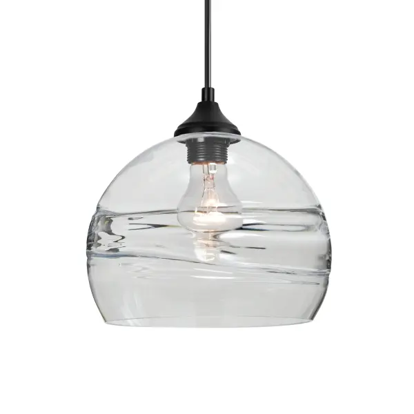The Spirit pendant features a clear glass globe with a distinctive circular optical pattern that creates dramatic light play. The layered ring design adds visual depth while showcasing the lamp filament for a modern aesthetic.