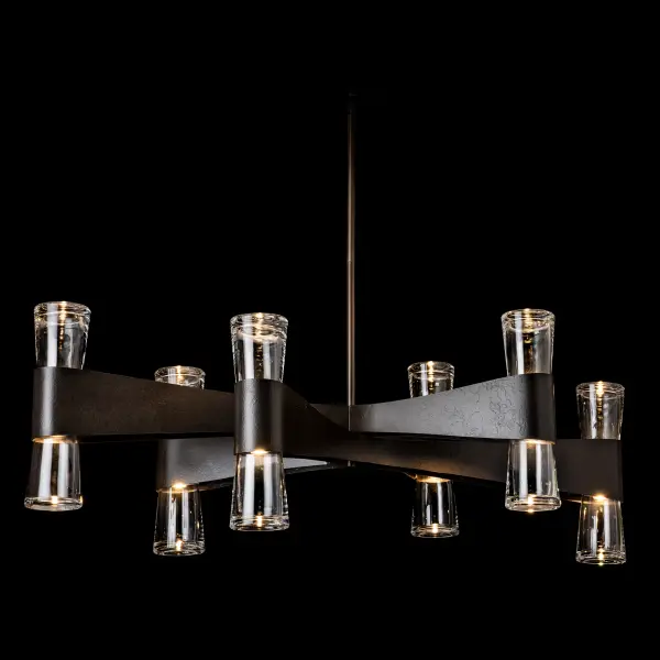 Artisanal forging on display, this grand Bellis chandelier gives an oval shape with its outstretched arms. Stunning, classic with a transitional style, the Bellis is a showstopper. Each of the six arms holds a duo of light. Up- and downlights are contained within crystal clear, thick, slightly flared glass. Available in any of our standard interior finishes. - alternate view