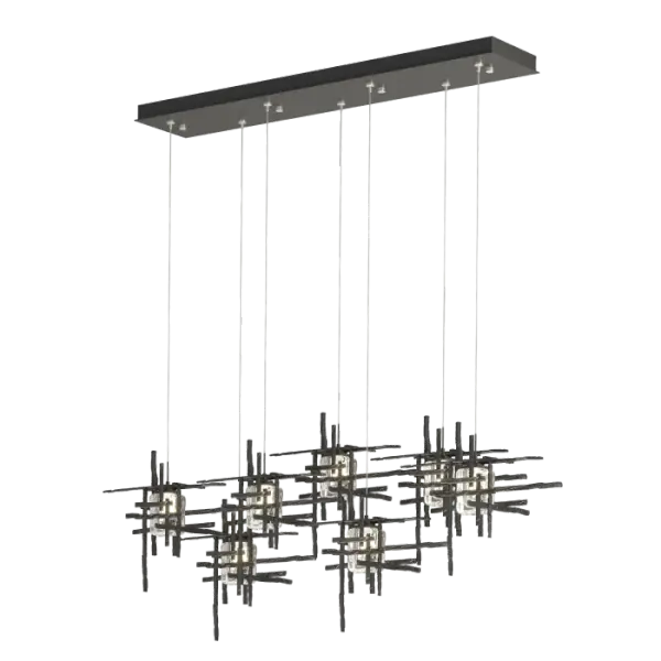 A linear multi-port pendant, this 7-Light Tura with its rectangular canopy offers both depth and dimension. Each intersecting piece is crafted from from annealed aluminum that are hand textured using a trip hammer and custom dies. This Tura Pendant's shades are made of thick, clear double layer seeded glass. Available in all standard finishes.
