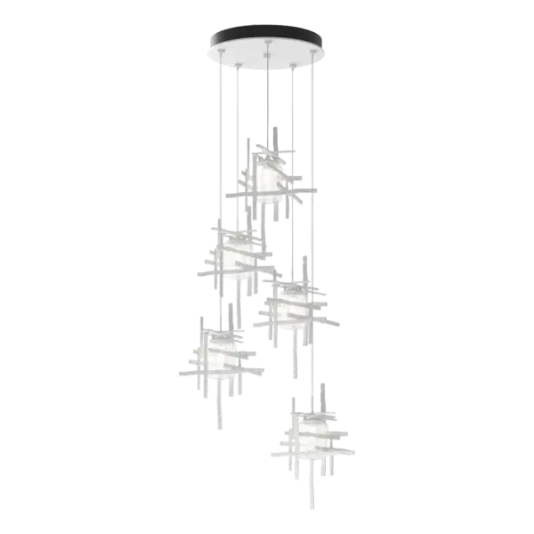 Thick, seeded clear glass shades are nestled within each of the Tura 5-Light Pendant’s modern, open, cage-like individual pendants. Perpendicular, intersecting pieces of hammered annealed aluminum, are painstakingly handmade with a trip hammer and dies by Vermont artisans. Easily customizable in length, the Tura is so versatile that you can feature it as a semi-flush or a longer pendant with cascading light with an easy cable adjustment.