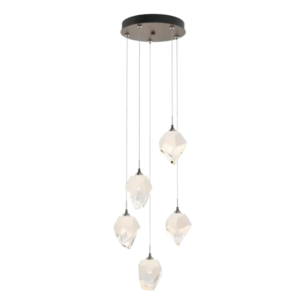 The Chrysalis 5-Light Small Crystal Pendant is a multi-port fixture that features five small, handcrafted faceted glass crystals suspended from a round canopy. A thick, clear layer of glass is encased in an outer cocoon of hand-blown, colored glass (matte black or white; all 5 are same color). The lower portion of the outer layer of glass is removed during a hand-polishing process to reveal the inner crystal clear layer below. Each crystal is lit from within. Customizable cable lengths can be shortened to create a dramatic semi-flush.