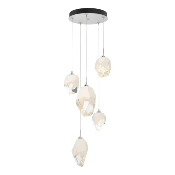 The Chrysalis 5-Light Mixed Crystal Pendant is a multi-port fixture that features five (2 large + 3 small), handcrafted faceted blown glass elements suspended from a round canopy. A thick, clear layer of glass is encased in an outer cocoon of hand-blown, colored glass (matte black or white; all 5 are same color). The lower portion of the outer layer of glass is removed during a hand-polishing process to reveal the inner crystal clear layer below. Each crystal is lit from within. Customizable cable lengths can be shortened to create a dramatic semi-flush.