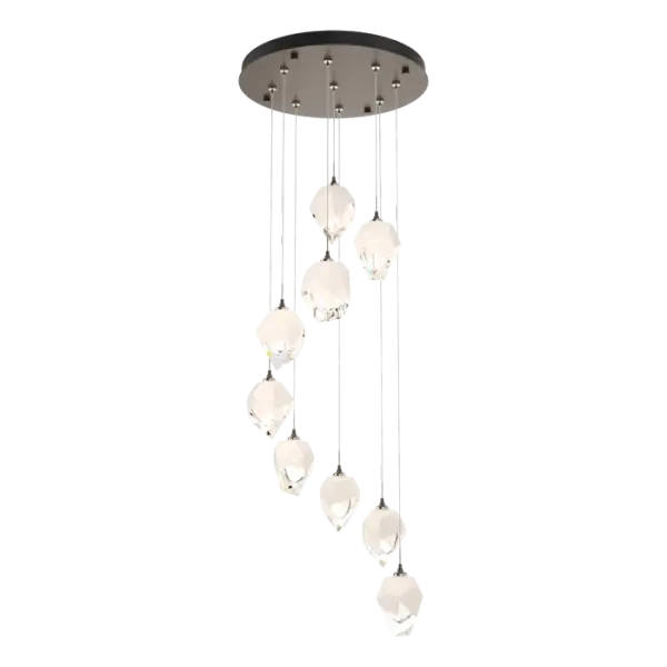 The Chrysalis 9-Light Small Crystal Pendant is the perfect focal piece for a stairwell or other central or corner space where cascading crystals lit from within create a waterfall of light when pendants are staggered. Highly-customizable, each individual crystal light is suspended via low-voltage cable from its round canopy. A thick, clear layer of glass is encased in an outer cocoon of hand-blown, colored glass (matte black or white; all 9 are same color). The lower portion of the outer layer of glass is removed by hand-polishing it, revealing the inner clear layer below.