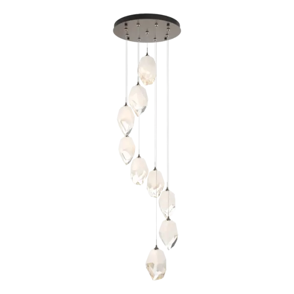 The Chrysalis 9-Light Large Crystal Pendant is the perfect focal piece for a stairwell or other central or corner space where cascading crystals lit from within create a waterfall of light when pendants are staggered. Highly-customizable, each individual pendant is suspended via low-voltage cable from its round canopy. A thick, clear layer of glass is encased in an outer cocoon of hand-blown, colored glass (matte black or white; all 9 are same color). The lower portion of the outer layer of glass is removed by hand-polishing it, revealing the inner clear layer below.
