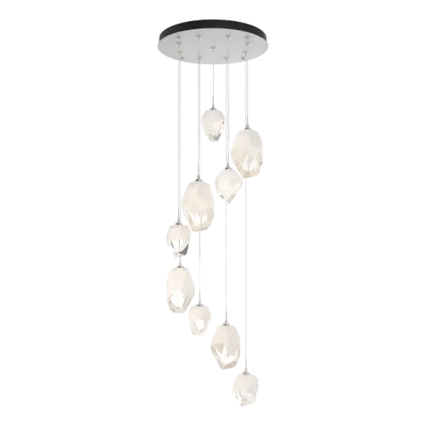 The Chrysalis 9-Light Mixed Crystal Pendant makes a statement in any stairwell or other central or corner space where cascading crystals lit from within create a waterfall of light when pendants are staggered. Highly-customizable, each individual pendant (4 large + 5 small) is suspended via low-voltage cable from its round canopy. A thick, clear layer of glass is encased in an outer cocoon of hand-blown, colored glass (matte black or white; all 9 are same color). The lower portion of the outer layer of glass is removed by hand-polishing it, revealing the inner clear layer below.
