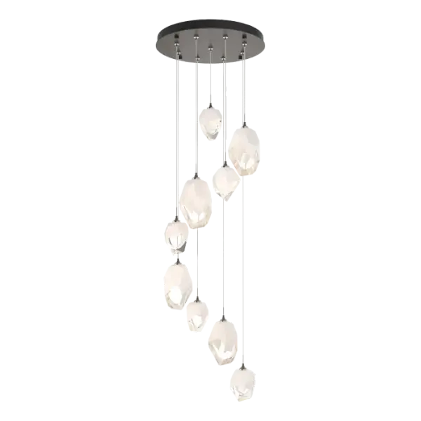The Chrysalis 9-Light Mixed Crystal Pendant makes a statement in any stairwell or other central or corner space where cascading crystals lit from within create a waterfall of light when pendants are staggered. Highly-customizable, each individual pendant (4 large + 5 small) is suspended via low-voltage cable from its round canopy. A thick, clear layer of glass is encased in an outer cocoon of hand-blown, colored glass (matte black or white; all 9 are same color). The lower portion of the outer layer of glass is removed by hand-polishing it, revealing the inner clear layer below.