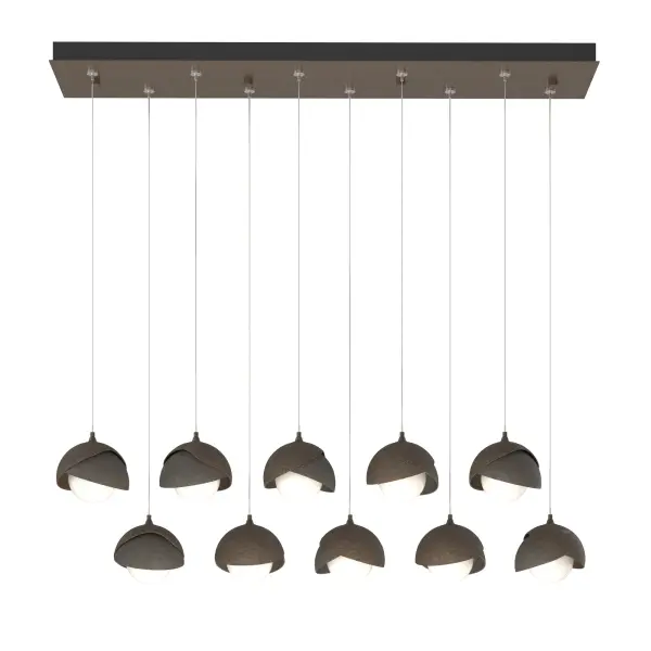 The Brooklyn Collection features fixtures in many sizes and formats, including this large 10-Light Double Shaded linear version. With its rectangular pendant above, ten individual pendants can be aligned or staggered to suit the design at customizable heights on each cable. The Brooklyn Double Shade is available as a two-tone option, with shades that can be in contrasting finishes, if desired. Vermont artisans hand-forge and texture each shade. Available in any standard finish.