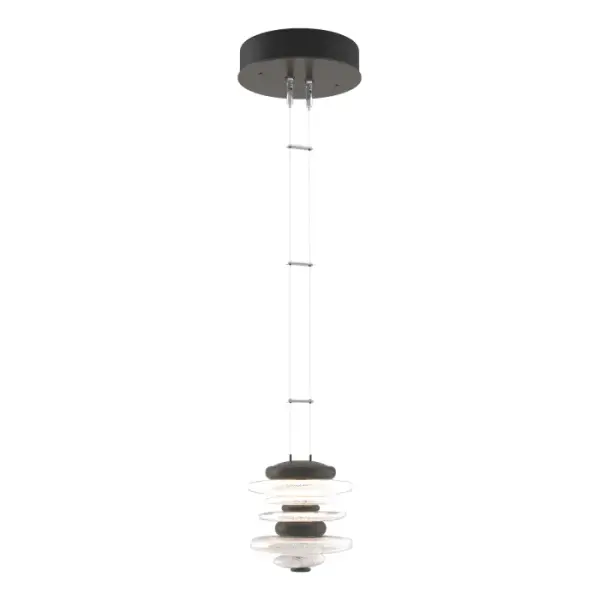 The Hubbardton Forge Cairn Pendant pays homage to the enigmatic stone sculptures, used since ancient times as landmarks. Thick hand-poured glass and cast steel “stones” are artistically stacked, and suspended by thin cables. Light flows over the steel and through the glass to seemingly glow from the inside. Also available as a Large Mini Pendant.