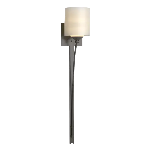 Our Formae Sconce offers a contemporary take on the traditional taper. A tube of curved steel slowly peals from the mounting plate to form a gentle arc under the glass of the cylinder. Forged and formed by our artisans, each piece is unique.