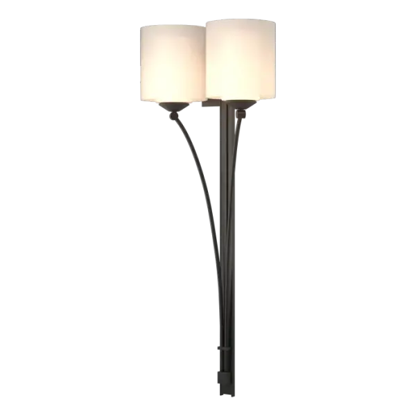 Our Formae double sconce offers a contemporary take on the traditional taper. Tubes of curved steel slowly peal from the central mounting plate to form gentle arcs under the glass of the cylinders. Forged and formed by our artisans, each piece is unique.