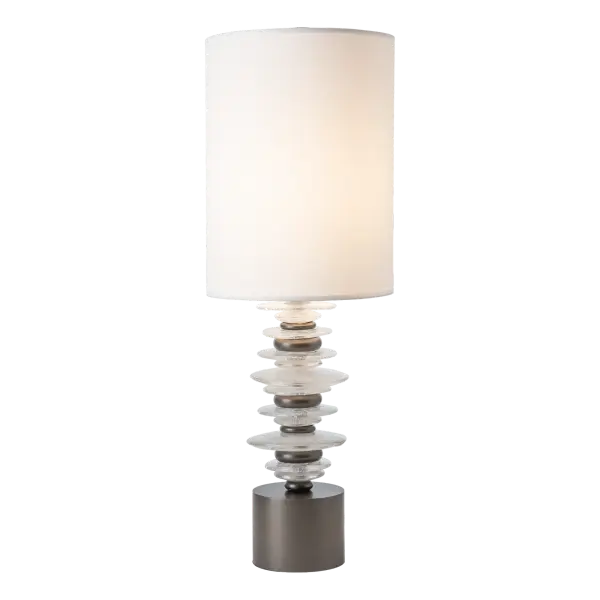 The Cairn Table Lamp is sleek and stylish. At 32" in height, it is tall enough to give substantial light to its surrounding surface. The Cairn features a dozen hand-poured glass "stones" intersperced with smaller steel "stone" elements. A tall cylindrical shade elevates the lamp's sophisticated allure.