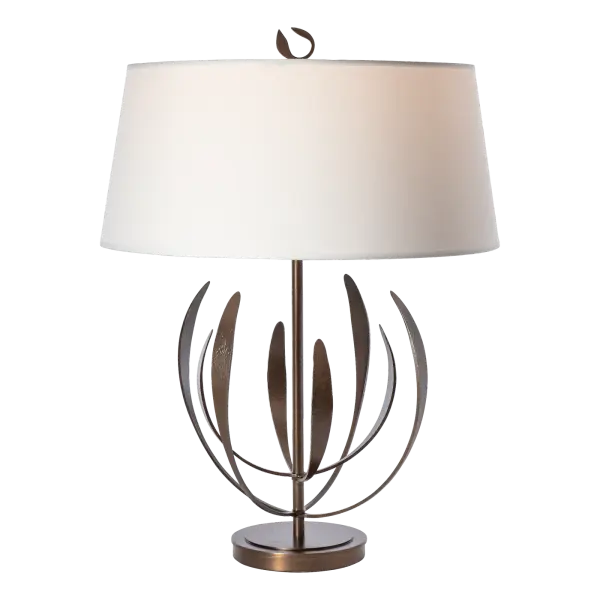 From our iconic Dahlia pendant comes this stunning table lamp designed by Paul Marr Hilliard. With two tiers of four upward reaching, delicate "petals" each, the Dahlia Table Lamp exudes grace and elegance. Petals are handcrafted by Vermont artisans in the 1800º red-hot fires of the forge. The finial detail is pure perfection, peeking out from above its beautiful fabric shade.