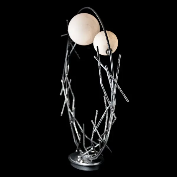 The Brindille Ring Lamp's nature-inspired artistry is reminiscent of Patrick Dougherty’s stickwork seen in nearby Middlebury VT. Each steel twig is hand-crafted and hammered creating the Brindille’s circular ring. It can be placed on a console table, floor area, or in a large wall alcove, or more. The Brindille’s unique glass globes feature a mottled, monochrome tortoiseshell pattern in white, adding an element of elegance and intrigue to its surroundings. - alternate view