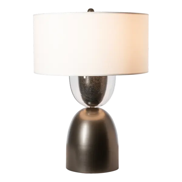 The Union Table Lamp demands attention in any space. A large lamp with a gently shaped steel lower and an upper half of forged steel encased in clear glass, this is a union of two opposing halves. The finial mimics their shape, adding to the details that make this lamp so special. A large, round fabric shade completes the aesthetic.