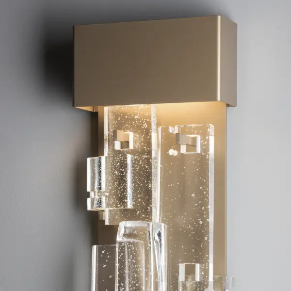 Fusion Large LED Sconce, a member of ART + ALCHEMY by Hubbardton Forge, is both elegant and functional, at over 25" in height. The staggered layers of clear, seeded, fused glass are displayed in a geometric pattern, set off by the lighting fixture's aluminum backplate. LED lighting is both economic and environmentally friendly, making for a stunning addition to any space.