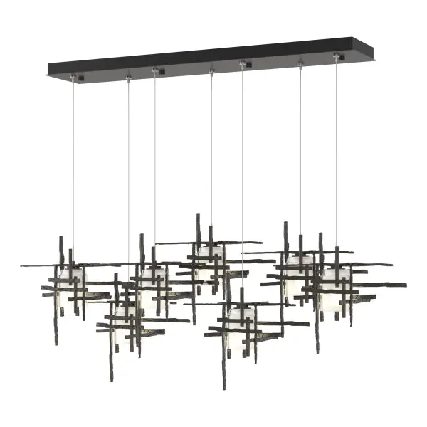 This 7-Light Tura with its rectangular canopy is a linear multi-port pendant, with both depth and dimension. Each intersecting piece is crafted from from annealed aluminum that are hand textured using a trip hammer and custom dies. This Tura Pendant's shades are made of simple, thick cylinders of frosted glass. Available in all standard finishes.