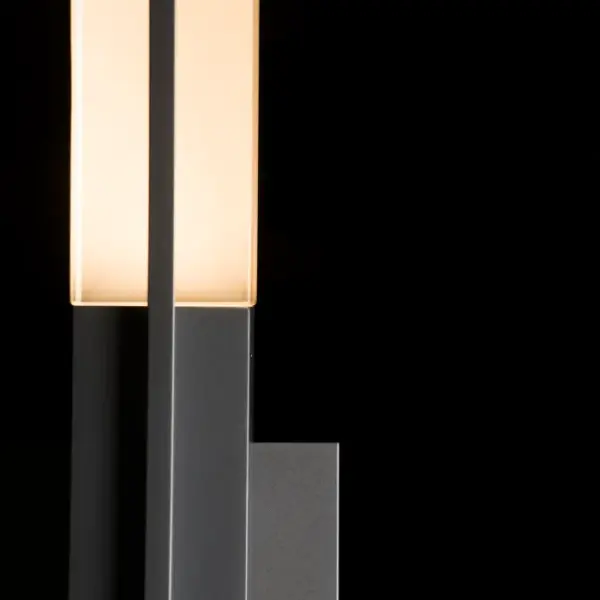 The clean contemporary lines and architectural profile of the Centre Large Outdoor Sconce create a design that complements transitional and contemporary exteriors alike. A single metal arm holds the thick bars of glass at either end—a wide central band bisecting the center. Available in two sizes, this sconce makes a straightforward and elegant statement.