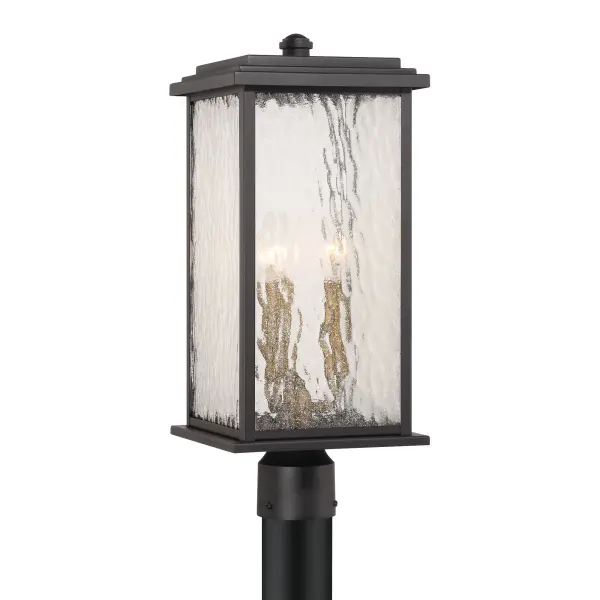 Brass with Rain Glassware The “Estate” Collection outdoor post radiates classic allure, with its black metal frame offering a striking contrast to the mesmerizing water glass panels. Encased within, vintage brass candle covers and intricate metalwork glow warmly, evoking a sense of nostalgic charm. Perfect for enhancing any outdoor space, this sconce blends classic sophistication with modern durability. - alternate view