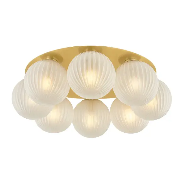 The Vernazza delivers chandelier-level drama in a close-to-ceiling format. Its oversized brass pan frames eight ribbed glass globes in an Art Deco-inspired design that balances minimalist structure with maximalist visual impact.