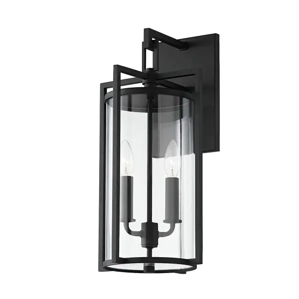 The Percy wall sconce blends transitional design with craftsman details, featuring sharp angular framing and a clear glass cylinder shade. Its textured black finish and wet-rated construction make it ideal for coastal and modern exteriors alike.