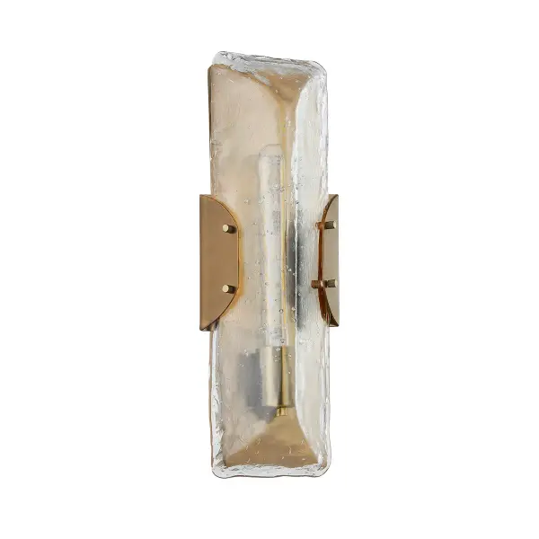 The Nordic wall sconce combines minimalist design with dramatic texture through its thick, seeded cast glass that sparkles when lit. The patina brass framework provides warm metallic contrast while maintaining a clean, architectural profile.