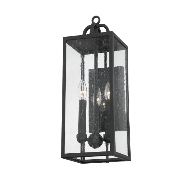 The Caiden outdoor wall sconce combines classic cage lantern styling with romantic farmhouse charm. Its forged iron frame and seeded glass create warm, natural light diffusion, while the decorative flower finial adds distinctive character.