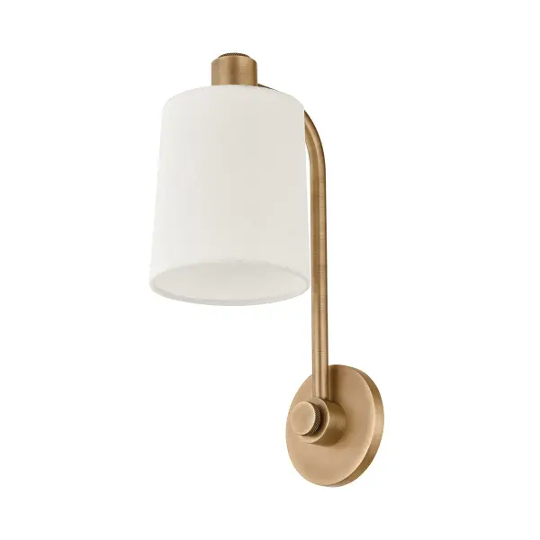 The Rigby wall sconce balances industrial minimalism with warmth through its curved L-shaped arm in patina brass and off-white linen drum shade. Compact at 6 inches wide, it delivers focused downlighting ideal for powder rooms and task areas.