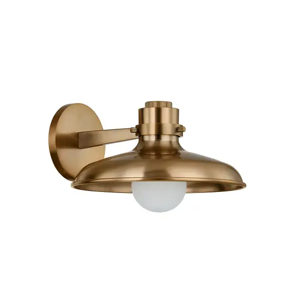 The Rainhill wall sconce combines retro charm with modern functionality. Its large metal dome shade directs light downward and outward, creating ambient warmth perfect for hallways and intimate spaces.