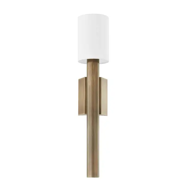 The Monty wall sconce makes a statement with its chunky rod-shaped arm and unique wedge backplate in warm patina brass. The thick metalwork creates architectural interest while the off-white linen shade softens the look.
