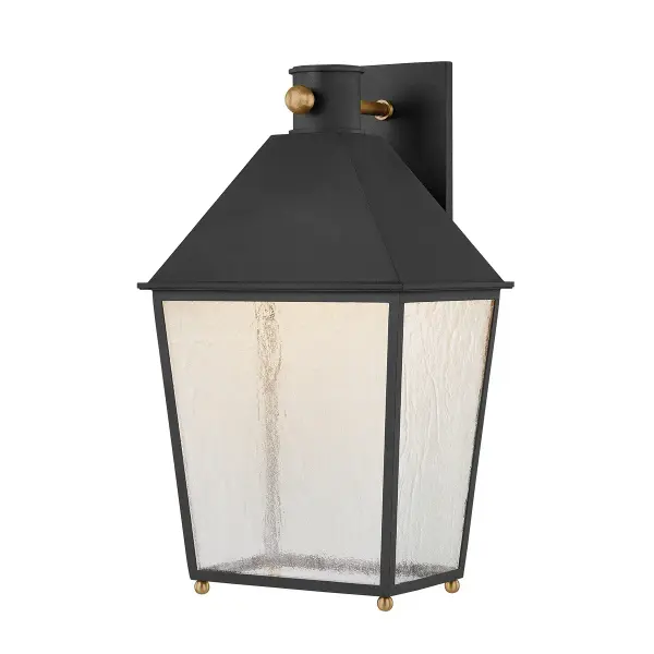 The Gladden wall sconce combines clean-lined lantern styling with textured black finish and patina brass accents. Heavy seeded glass creates soft, diffused light while the wet-rated construction ensures durability outdoors.