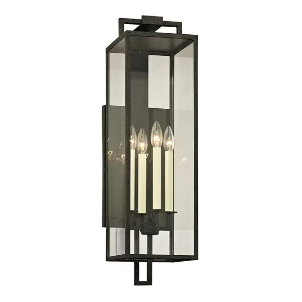 The Beckham wall lantern delivers commanding presence for large-scale exteriors with its elongated 28.5-inch silhouette. Four candelabra bulbs provide ambient illumination through clear glass panels, while hand-worked forged iron construction ensures durability.