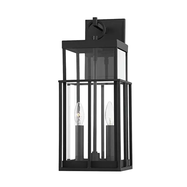 The Longport wall sconce reimagines the classic cage fixture with contemporary refinement. Its layered design—clear glass within a textured black aluminum frame—creates visual depth while the circular handle adds architectural interest.