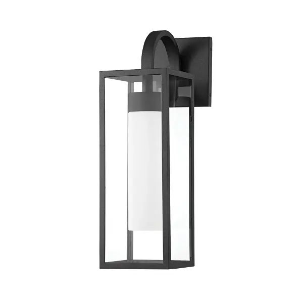 The Pax wall sconce brings industrial charm with a whimsical twist through its exaggerated swooping arm. The textured black aluminum frame paired with an elongated opal matte shade creates striking visual contrast while providing reliable outdoor illumination.